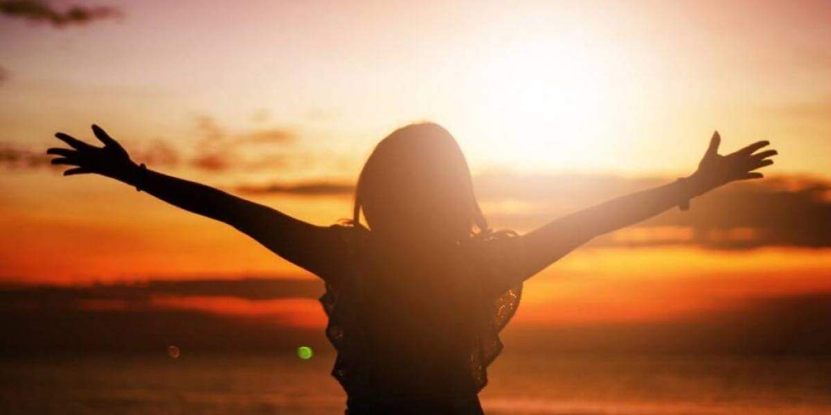 Foto de mulher com braços abertos para o sol